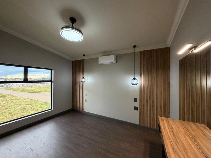 A modern, empty bedroom featuring timber slat wall accents, air conditioning, pendant lighting, and large windows with views.