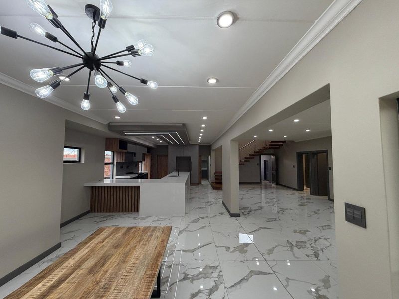 Spacious open-plan living and kitchen area featuring high-end marble-look floor tiles, modern recessed lighting, and a sleek kitchen island with contemporary cabinetry.
