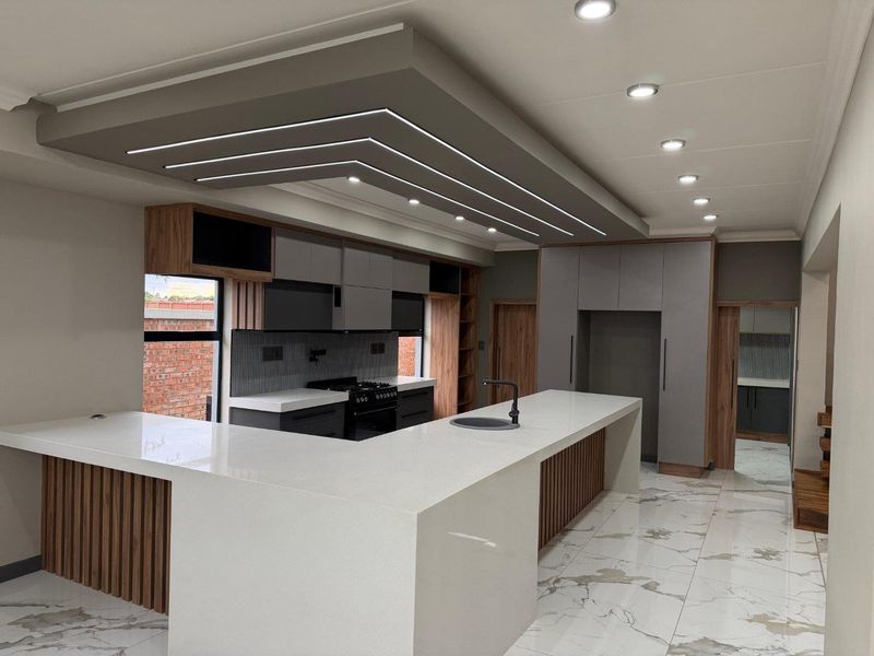 Modern, high-end kitchen featuring a large island with quartz countertops, custom cabinetry, integrated lighting, and premium finishes throughout.