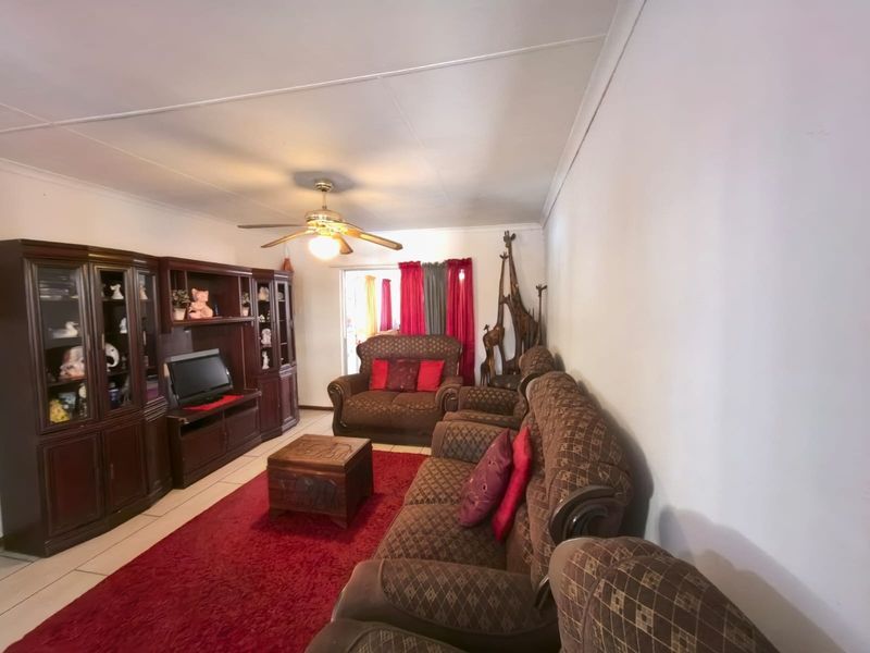 A living room featuring tiled flooring and a ceiling fan, providing a functional space with direct access to an outdoor area.