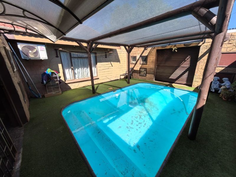 Enclosed pool area featuring a timber pergola with shade cloth, artificial turf surfacing, and a wall-mounted air conditioning unit.