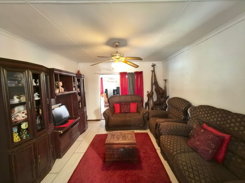A living room featuring tiled flooring, a ceiling fan, and coved ceilings, providing a functional space for relaxation.