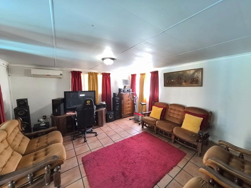 Spacious living room featuring tiled flooring and a wall-mounted air conditioning unit, offering a comfortable and functional layout for relaxation.