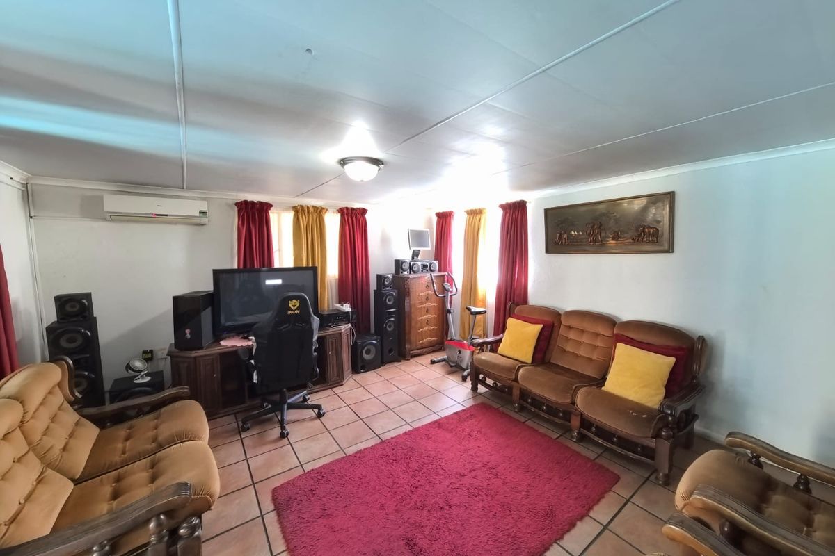 Spacious living room featuring tiled flooring and a wall-mounted air conditioning unit, offering a comfortable and functional layout for relaxation.
