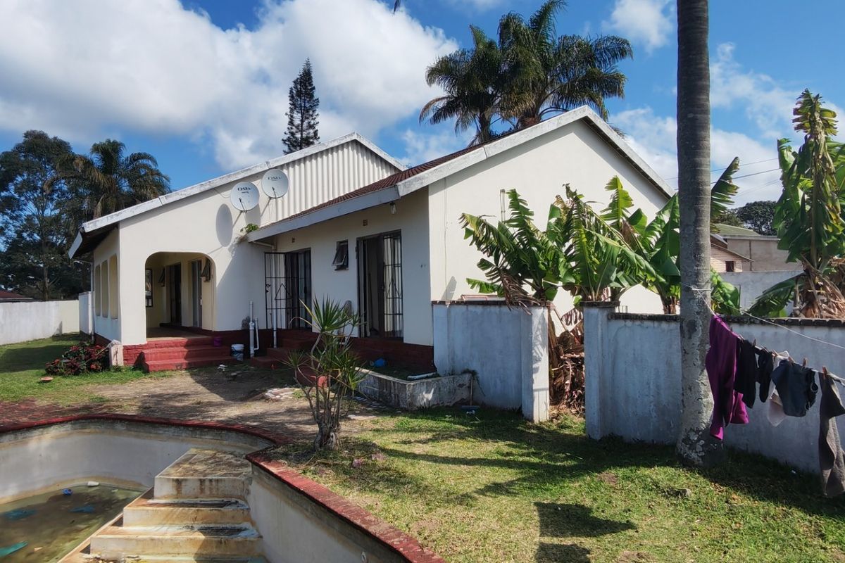 Rear view of the property featuring a swimming pool, covered patio area, and surrounding boundary walls with established garden space.