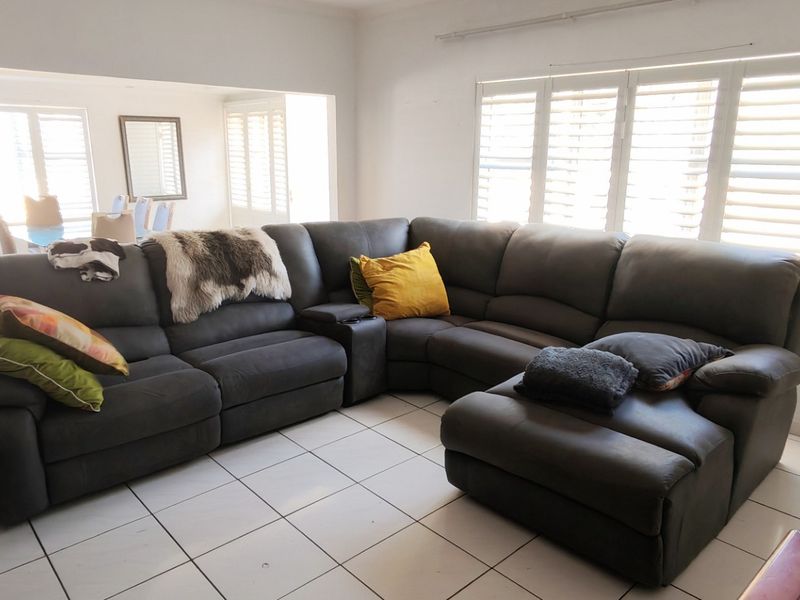 Spacious open-plan living area featuring neutral tiled flooring and plantation shutters, providing a bright and versatile space for relaxation and dining.