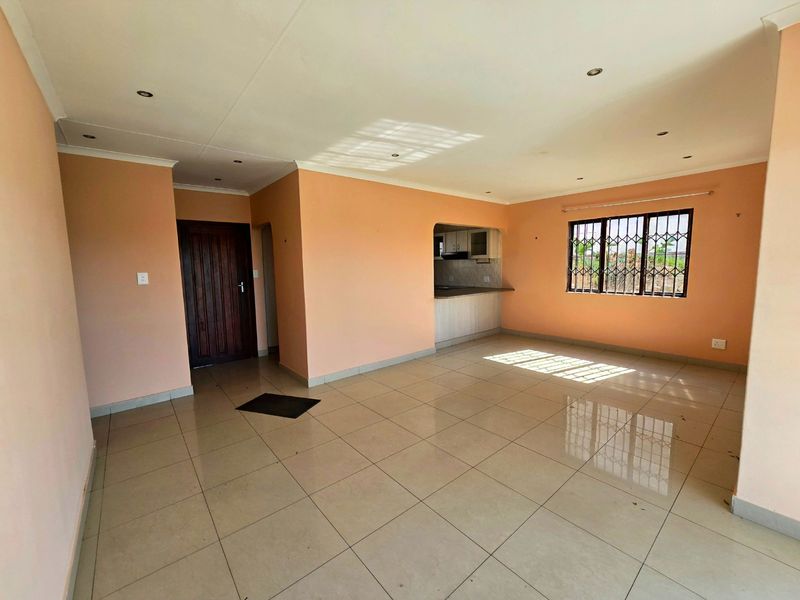 Spacious open-plan living area featuring neutral tiled flooring, recessed lighting, and a seamless transition into the adjacent kitchen space.