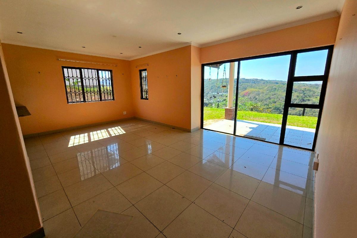 Spacious, empty living area featuring large sliding glass doors that open to a patio with scenic views, complemented by tiled flooring and recessed lighting.