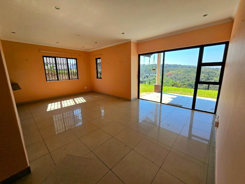 Spacious, empty living area featuring large sliding glass doors that open to a patio with scenic views, complemented by tiled flooring and recessed lighting.