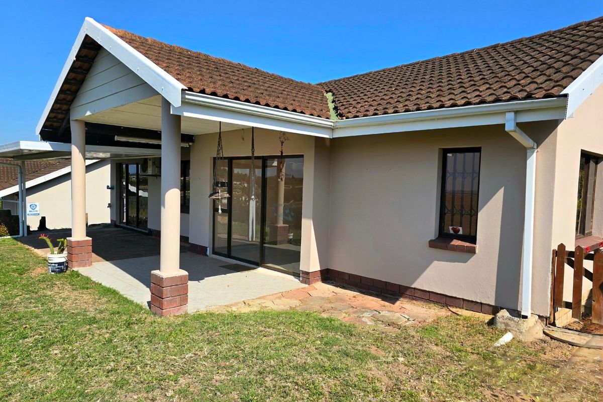 Rear view of the townhouse featuring a covered patio area, tiled roof, and sliding glass doors leading into the living space.