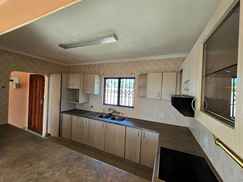 A functional kitchen featuring laminate cabinetry, laminate countertops, a double bowl sink, and an integrated electric hob with an extractor fan.