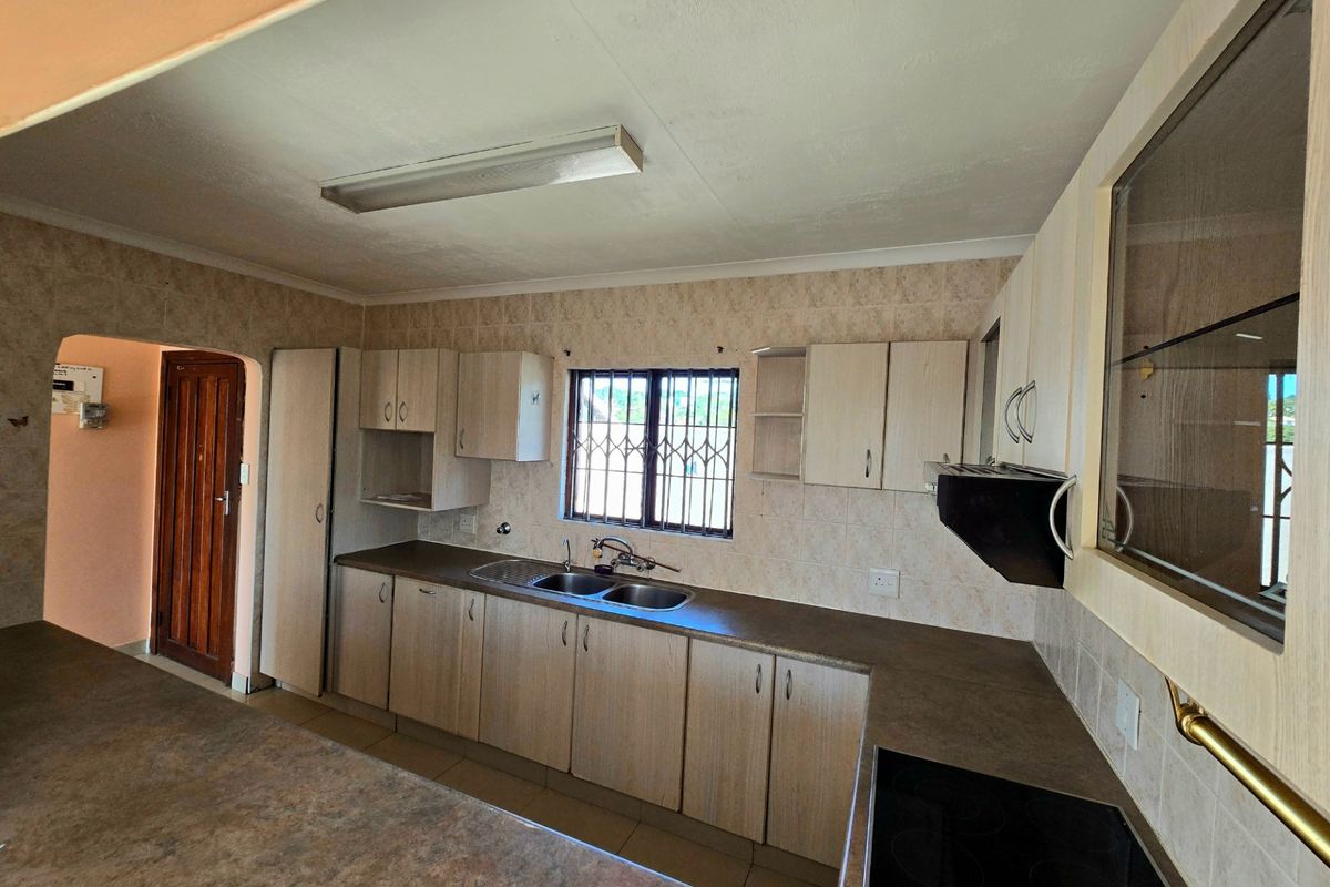A functional kitchen featuring laminate cabinetry, laminate countertops, a double bowl sink, and an integrated electric hob with an extractor fan.