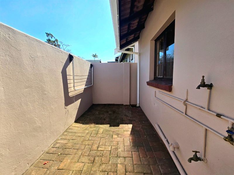 A functional outdoor utility courtyard featuring paved flooring, boundary walls, and external water taps, suitable for laundry or service tasks.