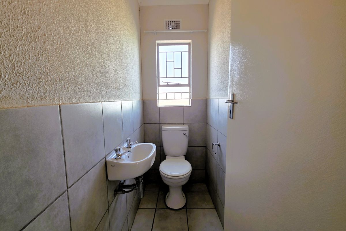 A compact guest bathroom featuring a wall-mounted basin, toilet, and neutral tiled finishes.