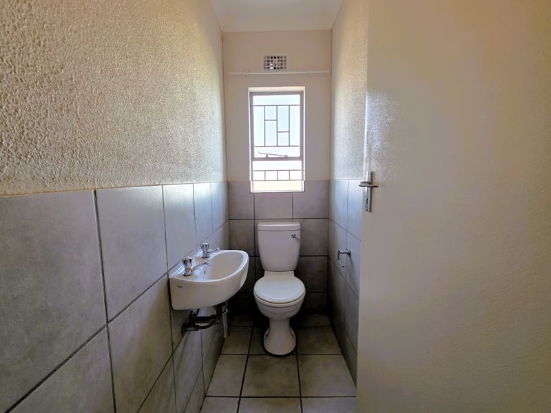 A compact guest bathroom featuring a wall-mounted basin, toilet, and neutral tiled finishes.
