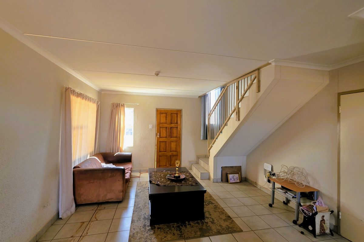 Living room featuring tiled flooring, a staircase with a wooden balustrade, and a solid wooden front door.
