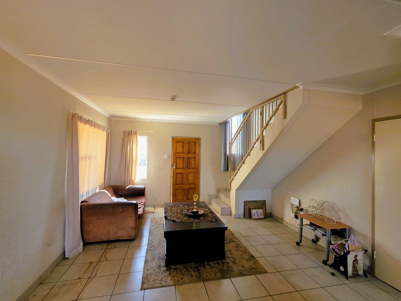 Living room featuring tiled flooring, a staircase with a wooden balustrade, and a solid wooden front door.