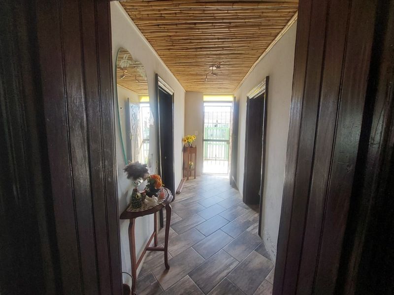 A well-lit hallway featuring unique bamboo ceiling detailing and durable tiled flooring, providing access to multiple rooms within the home.
