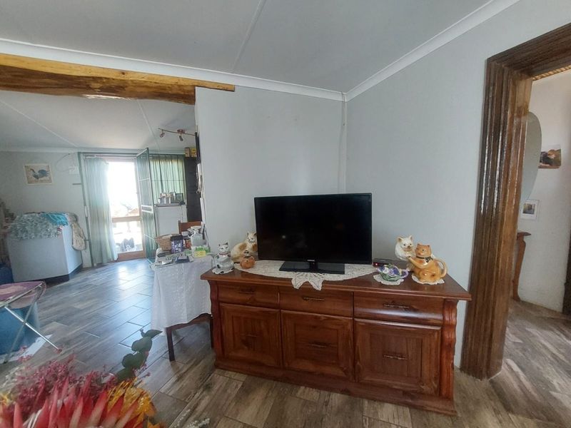 A living area featuring tiled flooring, coved ceilings, and an exposed timber beam, providing a view into the adjacent room.
