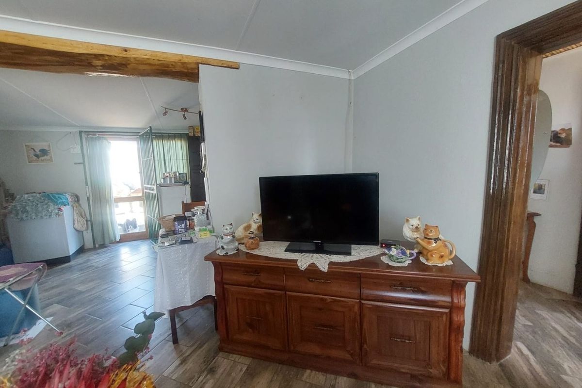 A living area featuring tiled flooring, coved ceilings, and an exposed timber beam, providing a view into the adjacent room.