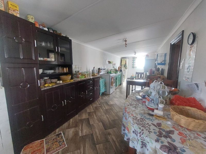 A functional kitchen area featuring dark wood-toned built-in cabinetry, a freestanding stove, and wood-look tiled flooring.