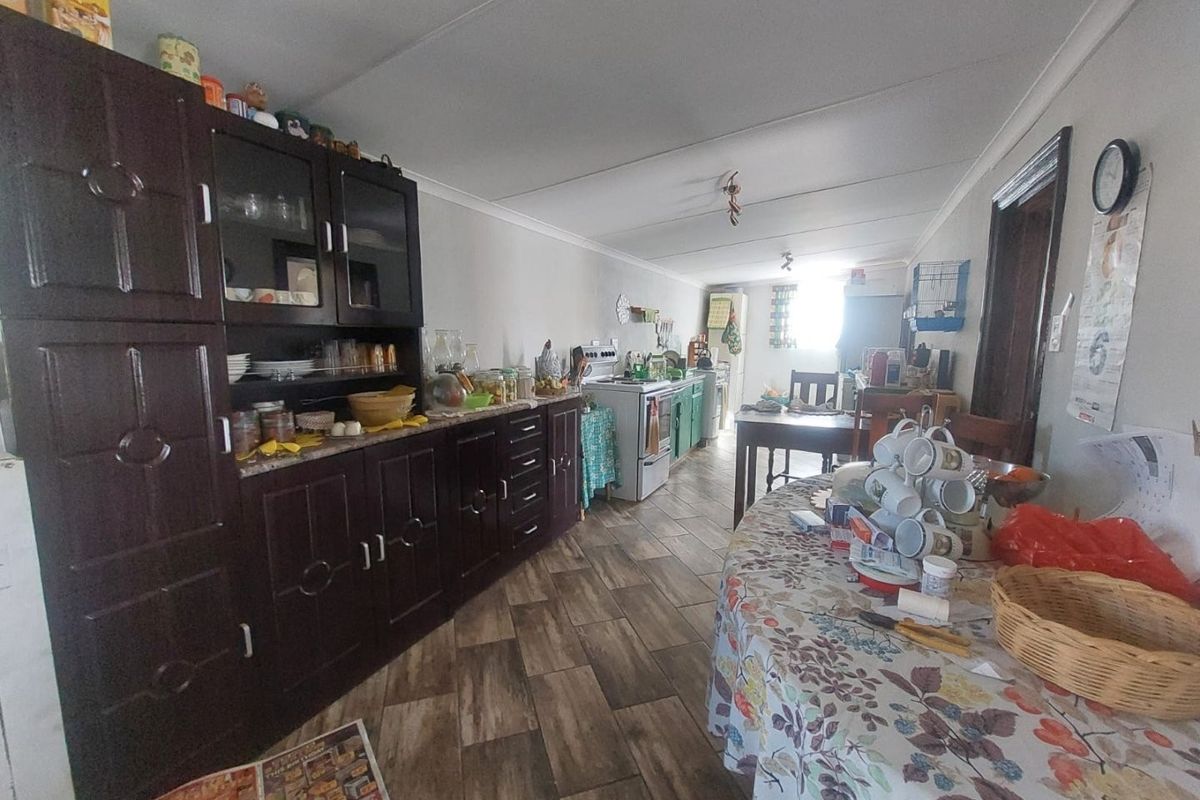 A functional kitchen area featuring dark wood-toned built-in cabinetry, a freestanding stove, and wood-look tiled flooring.