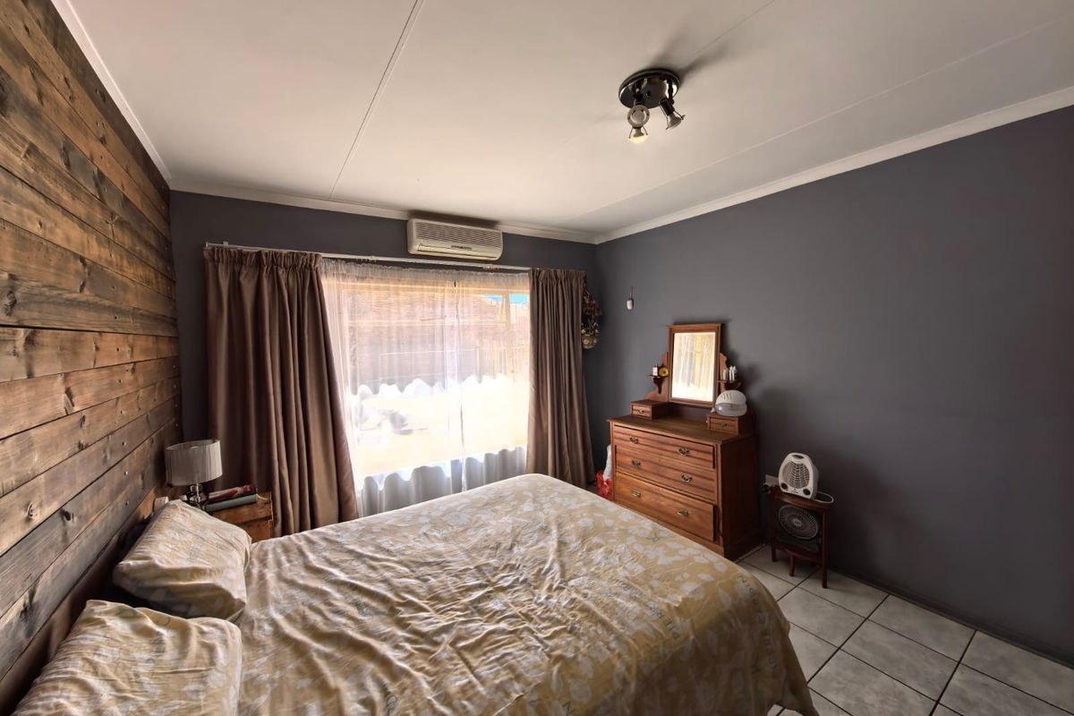A bedroom featuring timber wall cladding, tiled flooring, and a wall-mounted split-system air conditioner.