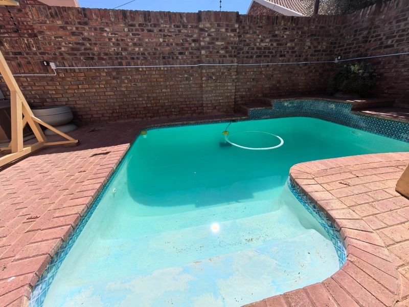 A private swimming pool area featuring brick paving and a high brick boundary wall, providing a secluded outdoor space.