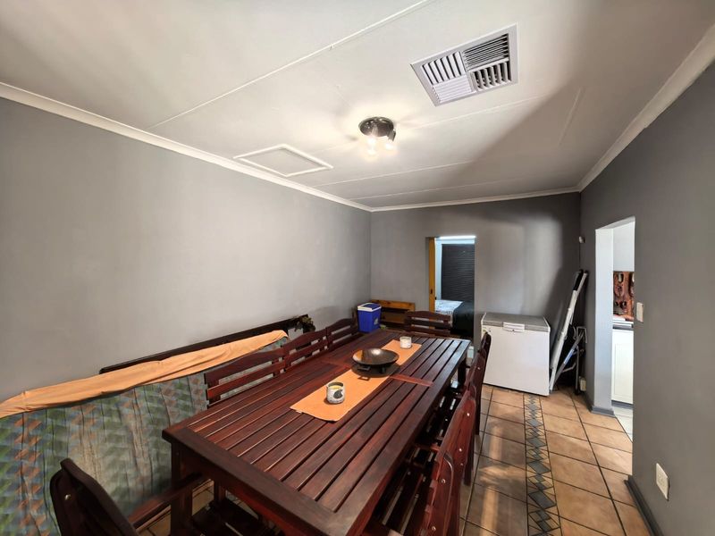 A functional dining area featuring tiled flooring, neutral wall tones, and a ceiling-mounted ventilation system.