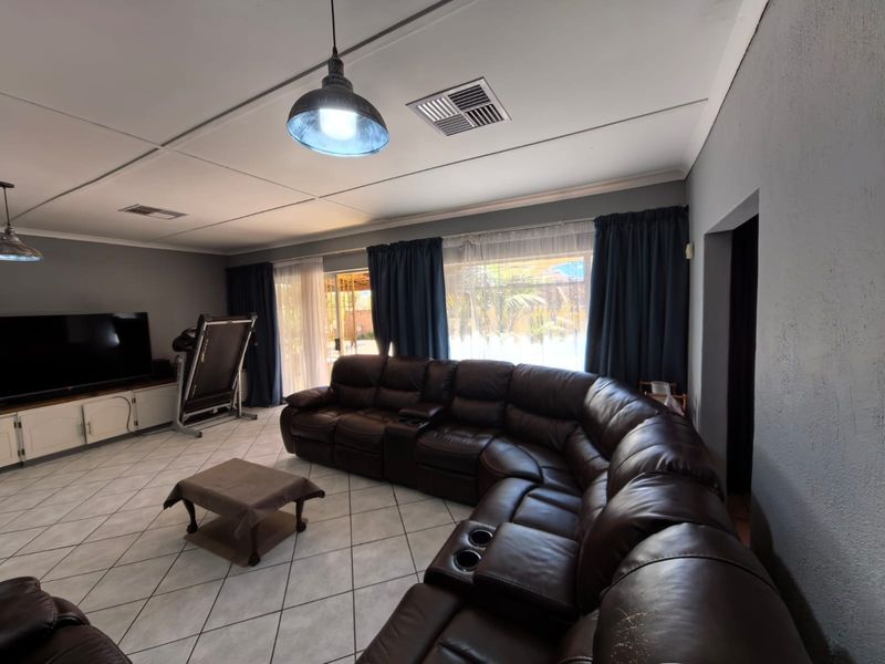 Spacious living room featuring tiled flooring, recessed ceiling air conditioning vents, and large sliding glass doors providing access to the outdoor area.