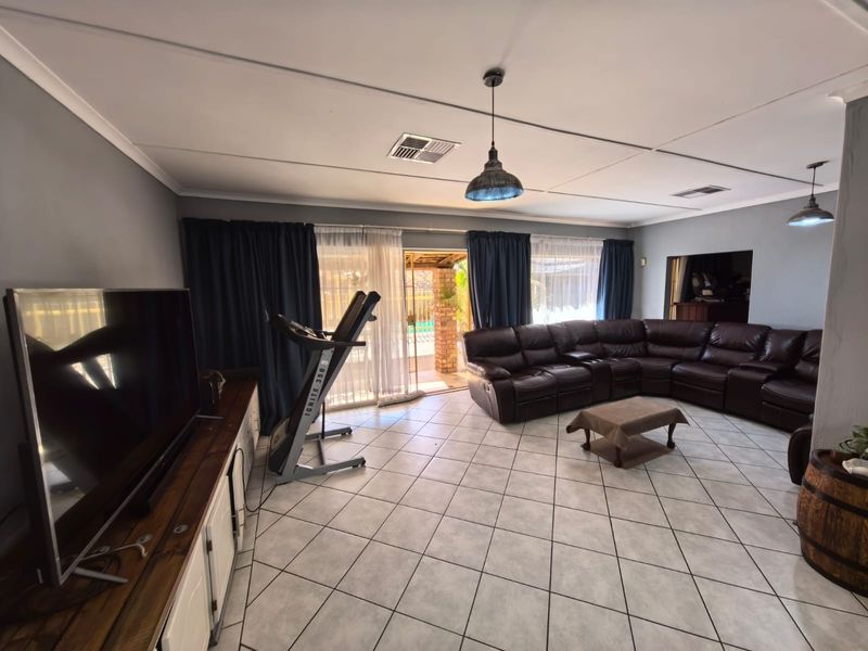 Spacious living room featuring tiled flooring, pendant lighting, and direct access to the outdoor patio area through sliding glass doors.