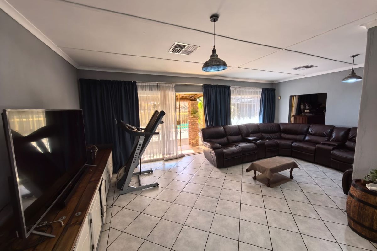 Spacious living room featuring tiled flooring, pendant lighting, and direct access to the outdoor patio area through sliding glass doors.