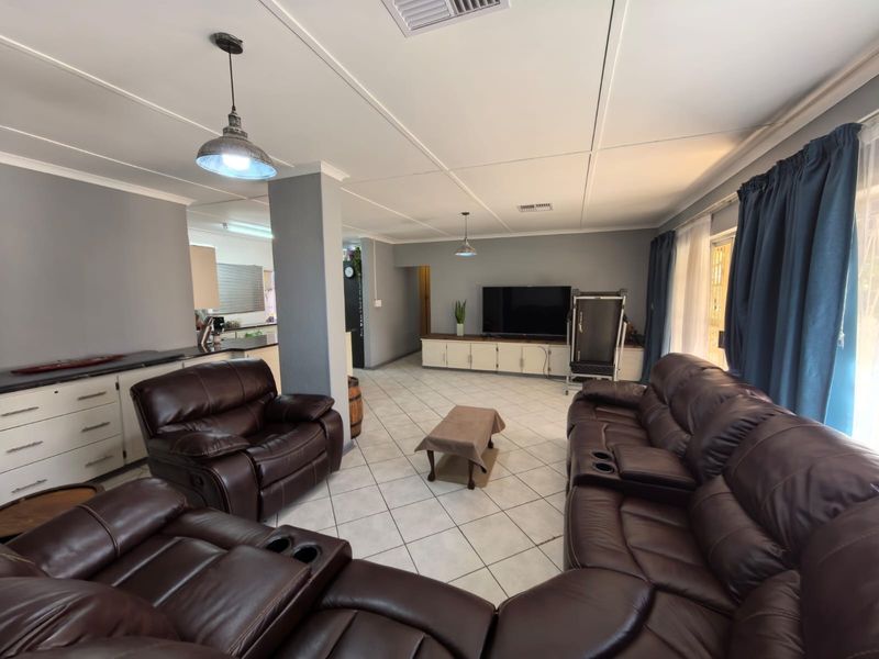 Spacious open-plan living area featuring tiled floors, built-in cabinetry, and integrated kitchen space with neutral grey walls and modern pendant lighting.