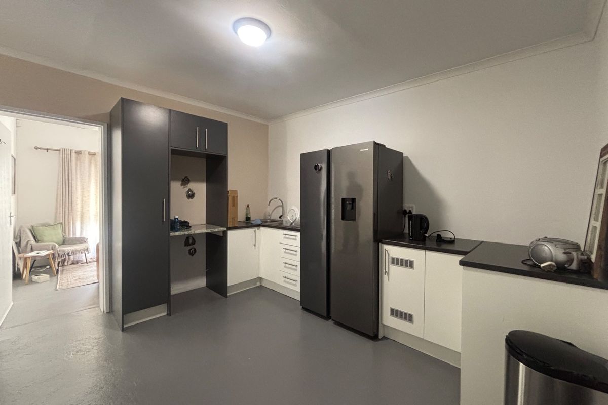A functional kitchen featuring modern two-tone cabinetry, laminate countertops, and a stainless steel sink, providing a clean and practical workspace.