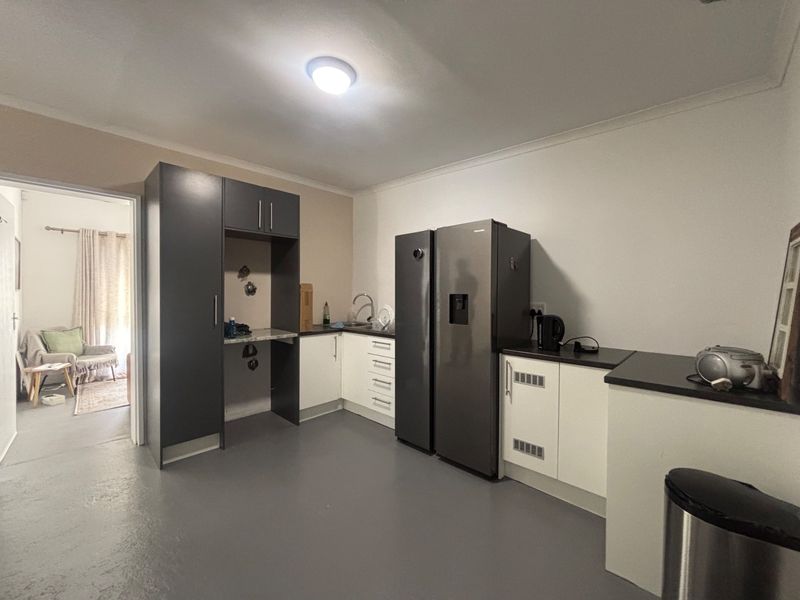 A functional kitchen featuring modern two-tone cabinetry, laminate countertops, and a stainless steel sink, providing a clean and practical workspace.
