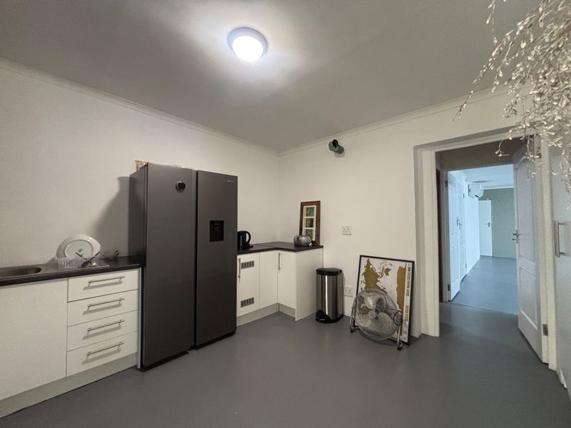 A functional scullery area featuring white built-in cabinetry, dark laminate countertops, and a stainless steel sink, providing additional prep and storage space.
