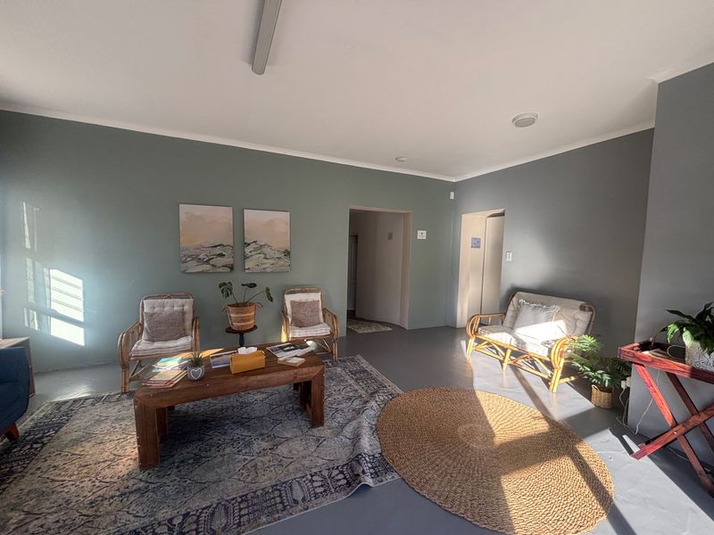 A bright and spacious commercial waiting area or lounge featuring smooth concrete floors, neutral painted walls, and recessed ceiling lighting.