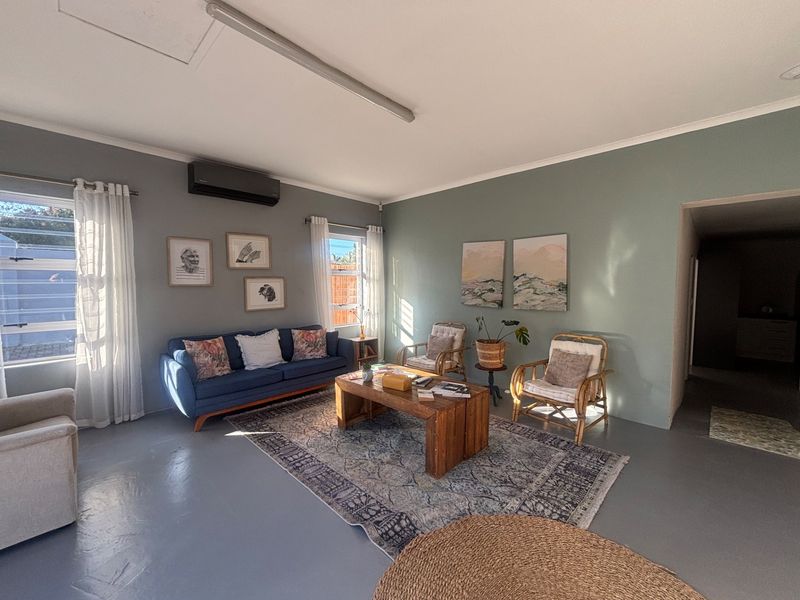 A bright and spacious living area featuring painted concrete floors, split-system air conditioning, and large windows allowing for ample natural light.