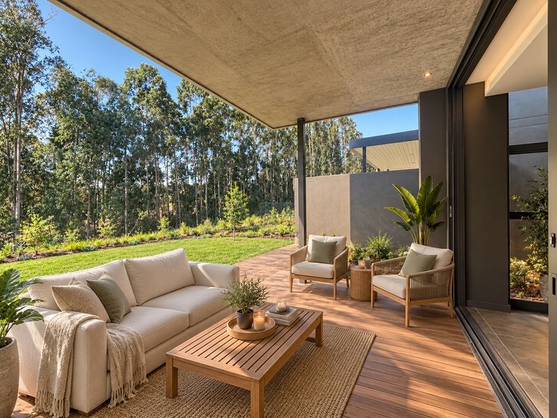A modern covered patio featuring timber decking, a concrete ceiling, and seamless access to the garden through large sliding glass doors.