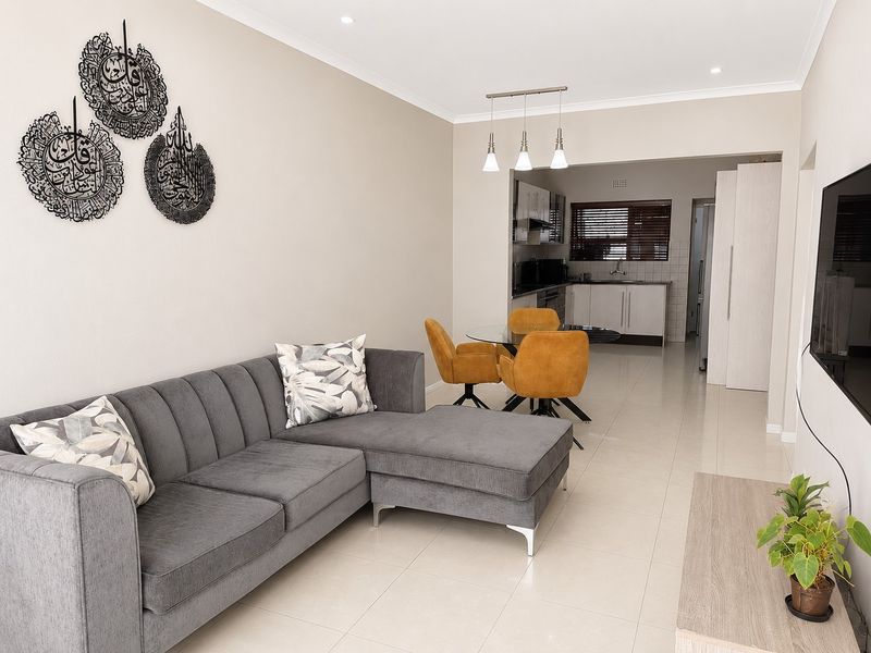 An open-plan living and dining area featuring neutral tiled floors, recessed lighting, and a modern kitchen with built-in cabinetry and appliances.