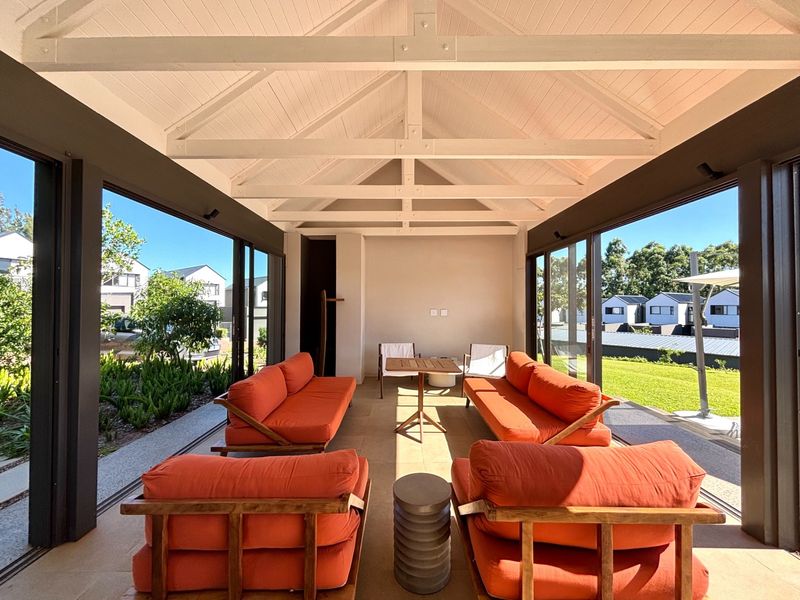 A spacious covered patio featuring an exposed timber truss ceiling, tiled flooring, and large sliding glass doors opening to the garden.