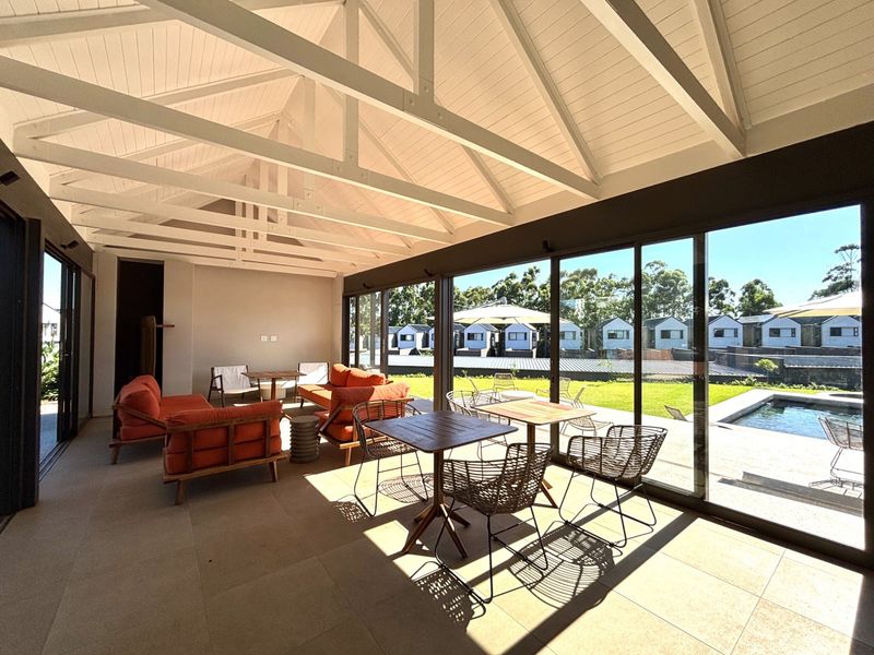 Spacious covered patio featuring a vaulted ceiling with exposed rafters, large sliding glass doors, and seamless indoor-outdoor flow to the pool area.