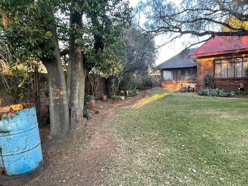 A view of the rear garden featuring a brick house exterior with a tiled roof and established trees.