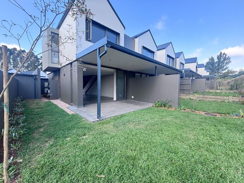 Modern townhouse rear elevation featuring a covered tiled patio, private garden, and large sliding glass doors leading into the open-plan living area.