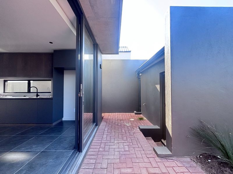 A modern paved outdoor patio area seamlessly connected to the interior kitchen space through large sliding glass doors.