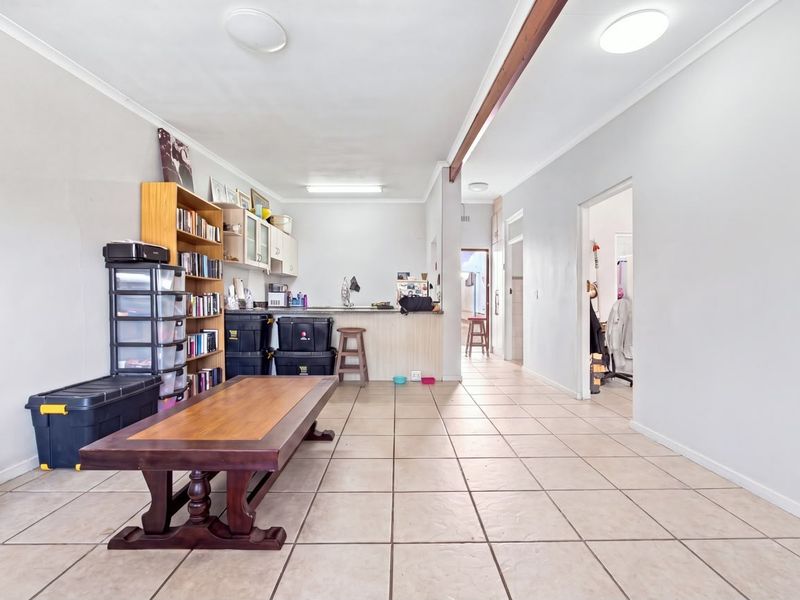 Open plan living and kitchen area featuring tiled flooring, a breakfast bar, and built-in cabinetry, offering a functional layout for daily living.