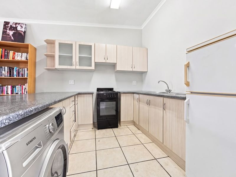 Functional kitchen featuring light wood-tone cabinetry, granite-look countertops, a stainless steel sink, and a freestanding oven, with tiled flooring throughout.
