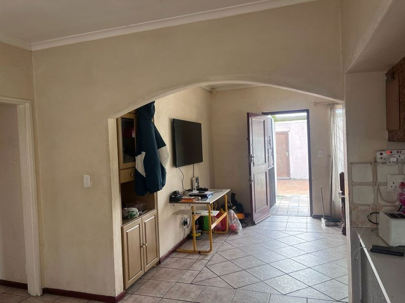 Living area featuring tiled flooring, an arched architectural detail, and direct access to the exterior through a doorway.