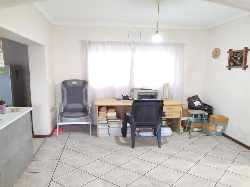 Open plan living area featuring tiled flooring and a kitchen breakfast bar, offering a versatile space for dining or home office use.