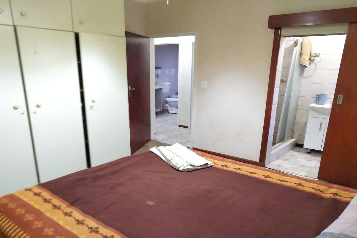 Bedroom featuring built-in cupboards and direct access to an en-suite bathroom with a shower.